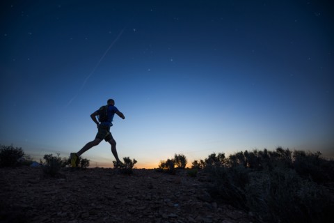 Silhouette of Caucasian teenage boy running at dawn