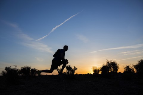 Silhouette of Caucasian teenage boy running at dawn