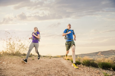 Caucasian couple running on remote hilltop