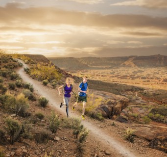 Caucasian couple running on remote dirt path