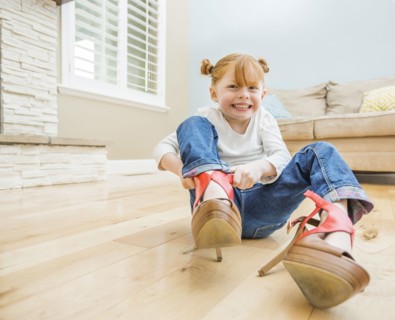 Caucasian girl wearing adult shoes in living room