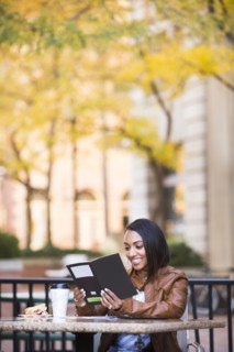 Indian woman reading booklet at outdoor cafe