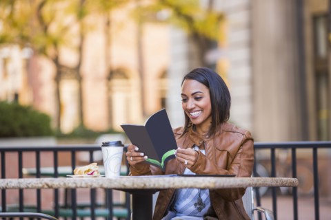 Indian woman reading booklet at outdoor cafe