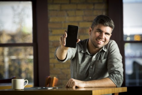 Caucasian man showing cell phone in cafe
