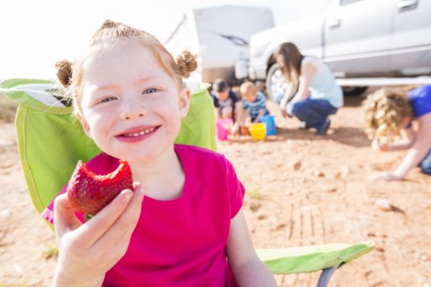 Caucasian girl eating strawberry while camping