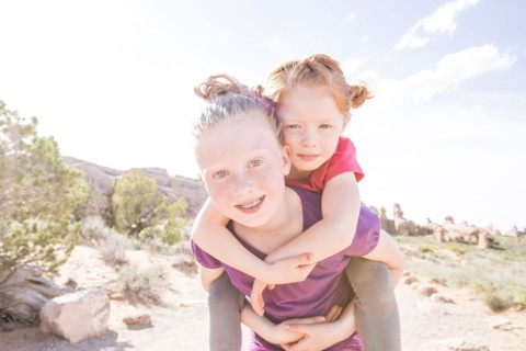 Caucasian girl carrying sister piggyback