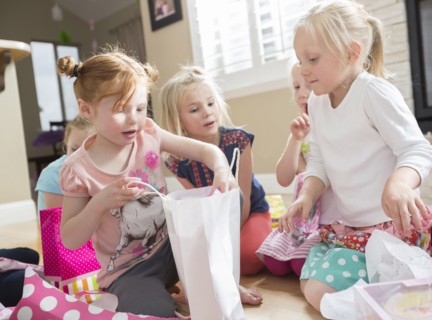 Caucasian girl opening gifts at party