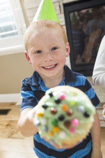 Caucasian boy wearing party hat showing cupcake
