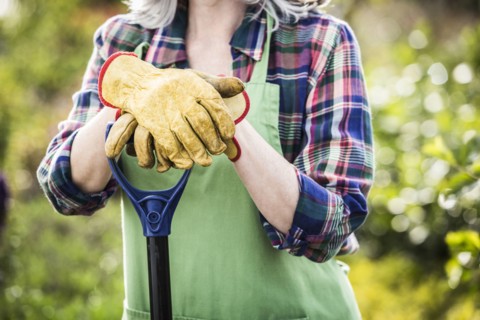 Caucasian woman wearing gloves holding shovel