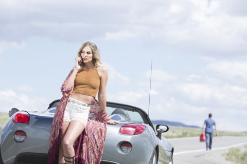 Caucasian woman talking on cell phone at vehicle breakdown