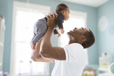 Black father lifting baby son