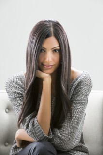Portrait of serious Indian woman sitting on sofa