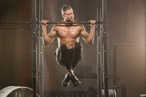 Caucasian man doing chin-up in gymnasium
