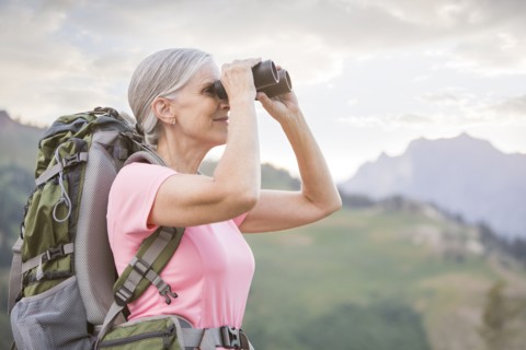 Caucasian woman hiking on mountain using binoculars