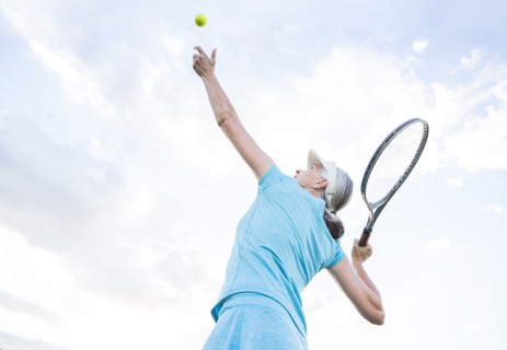 Caucasian woman serving tennis ball