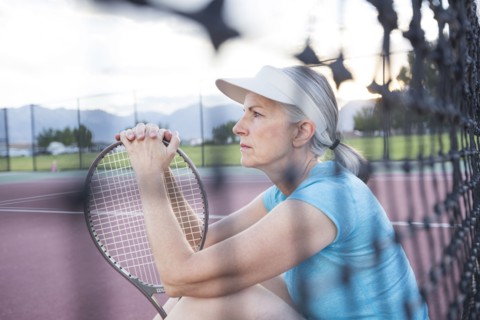 Caucasian woman resting and holding tennis racket
