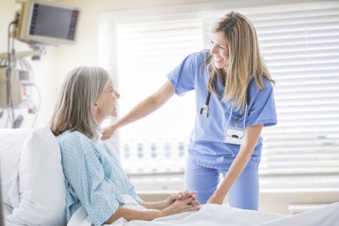 Caucasian nurse talking with woman in hospital bed
