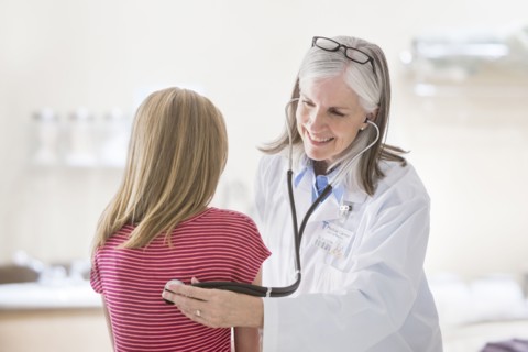 Caucasian doctor listening to chest of girl