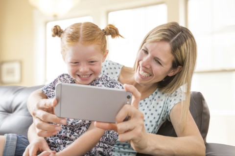 Caucasian mother and daughter posing for cell phone selfie