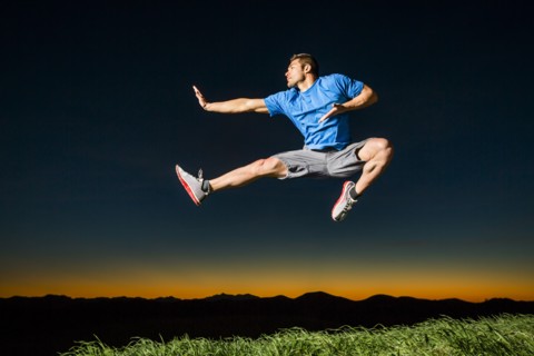 Caucasian man jumping at sunset