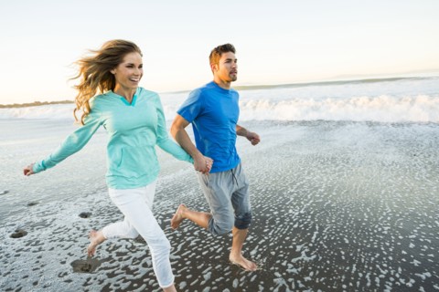 Couple holding hands running on beach