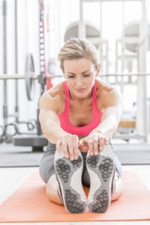 Woman stretching legs on exercise mat in gymnasium