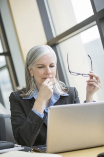 Pensive Caucasian businesswoman using laptop