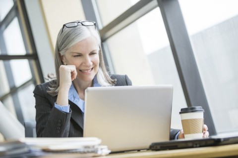 Smiling Caucasian businesswoman using laptop