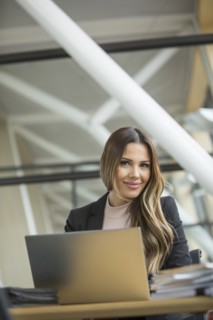 Smiling Mixed Race businesswoman using laptop