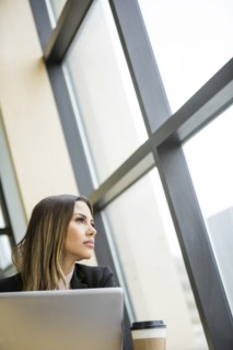 Mixed Race businesswoman with laptop daydreaming