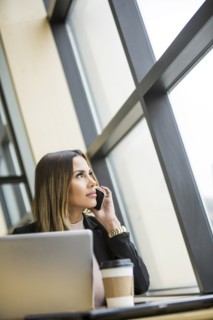 Mixed Race businesswoman talking on cell phone near laptop