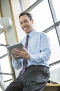 Smiling Mixed Race businessman using digital tablet
