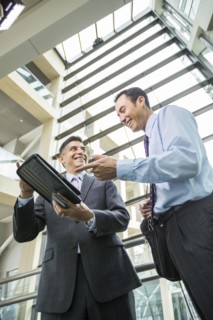 Smiling businessmen using digital tablet in lobby
