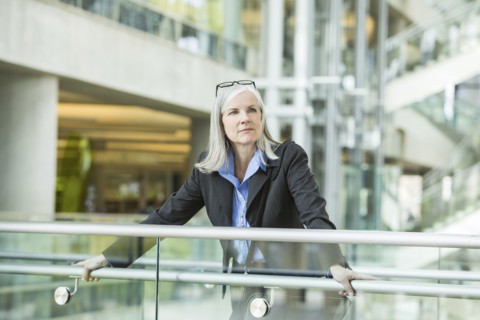 Portrait of serious Caucasian businesswoman leaning on railing in lobby