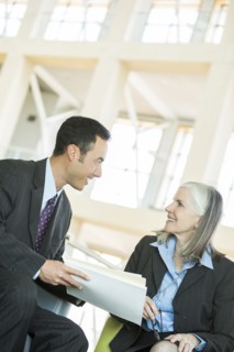 Smiling business people reading paperwork in lobby
