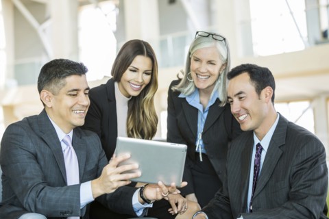 Smiling business people reading digital tablet in lobby