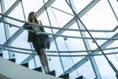 Pensive Mixed Race businesswoman standing on staircase
