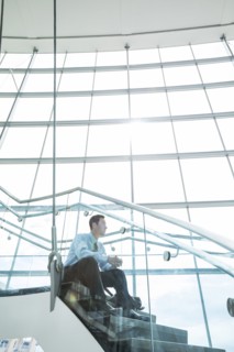 Pensive Mixed Race businessman sitting on staircase