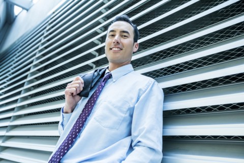 Portrait of smiling Mixed Race businessman leaning on wall
