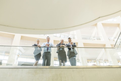 Portrait of smiling business people leaning on railing in lobby
