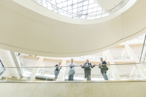 Portrait of smiling business people leaning on railing in lobby