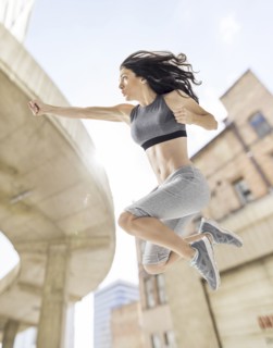 Caucasian woman jumping and punching in city