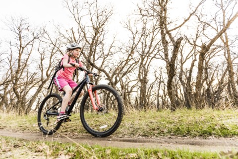 Caucasian girl riding bicycle on forest path
