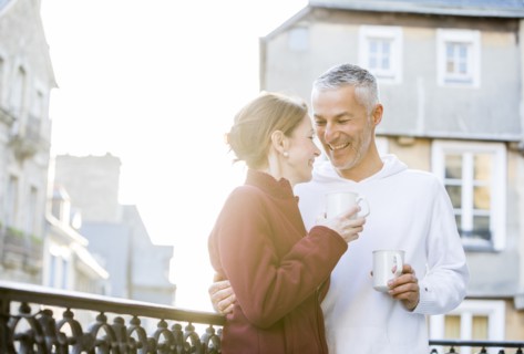 Caucasian couple drinking coffee on balcony in city