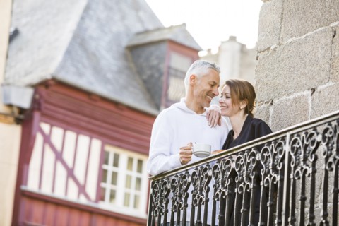 Caucasian couple drinking coffee on balcony in city