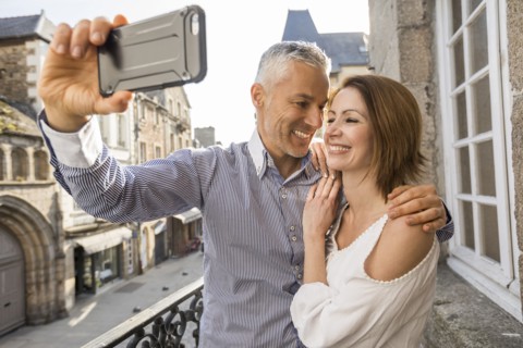 Caucasian couple posing for cell phone selfie