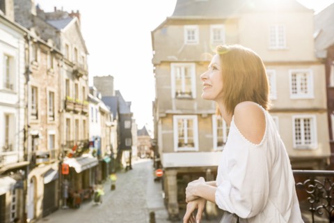 Caucasian woman leaning on balcony in city