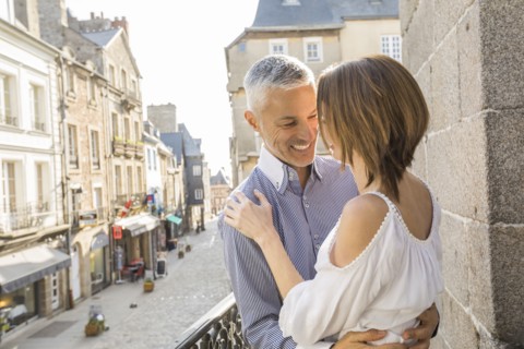 Caucasian couple hogging on balcony in city
