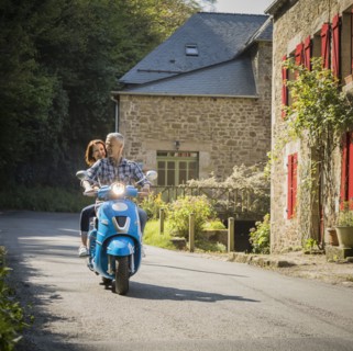 Caucasian couple riding blue motor scooter
