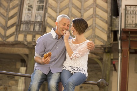 Caucasian couple eating bread on railing